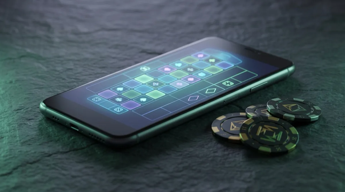 Smartphone on slate displaying a grid of casino game apps beside casino chips
