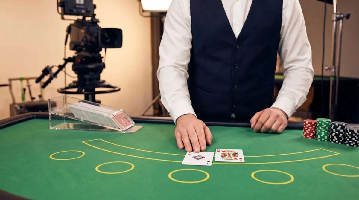 Live-dealer blackjack table with an ace and king dealt, card shoe and chip stacks